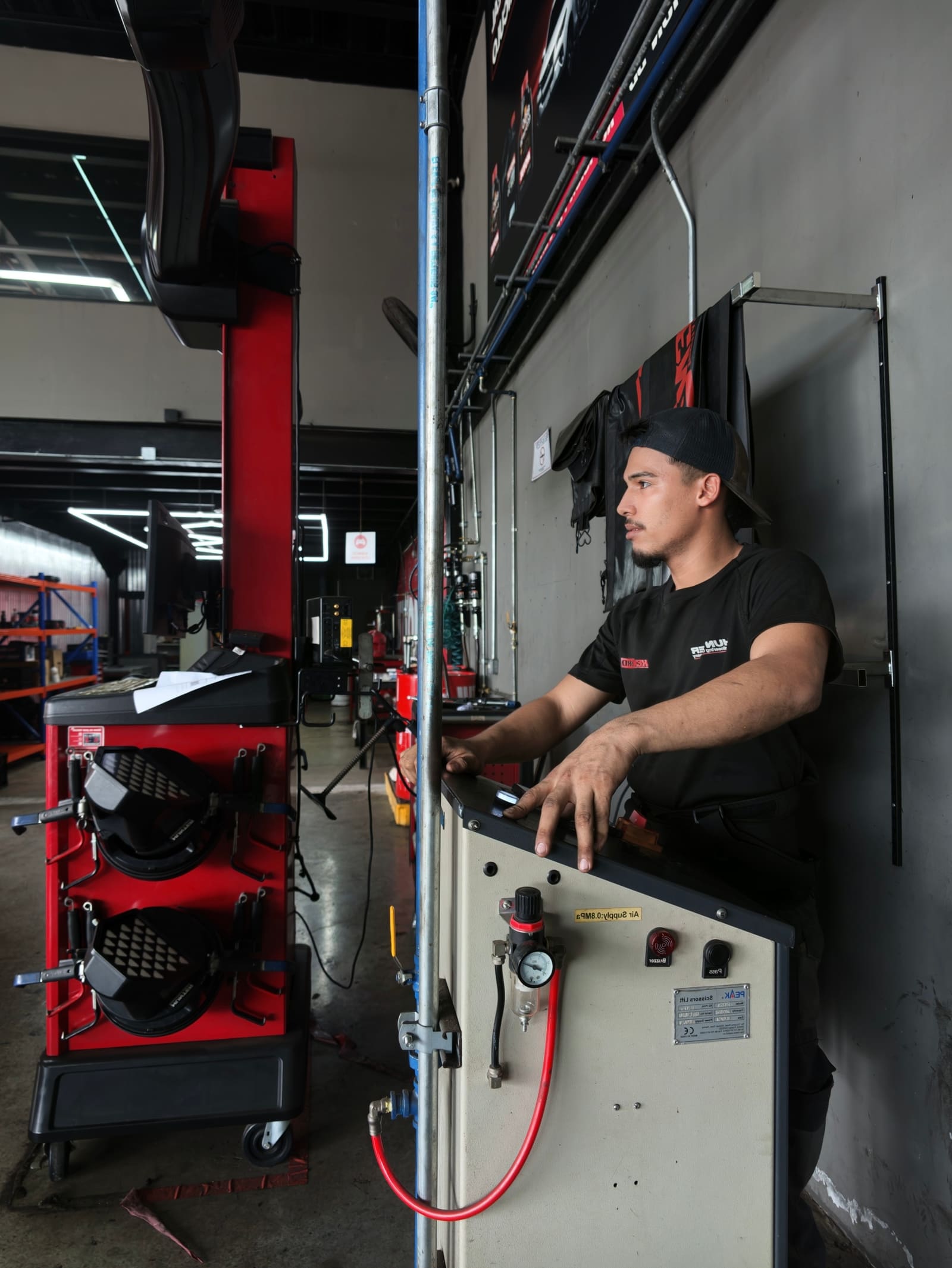 Técnico de Kenbro operando la consola de la alineadora Hunter junto a la torre roja de sensores